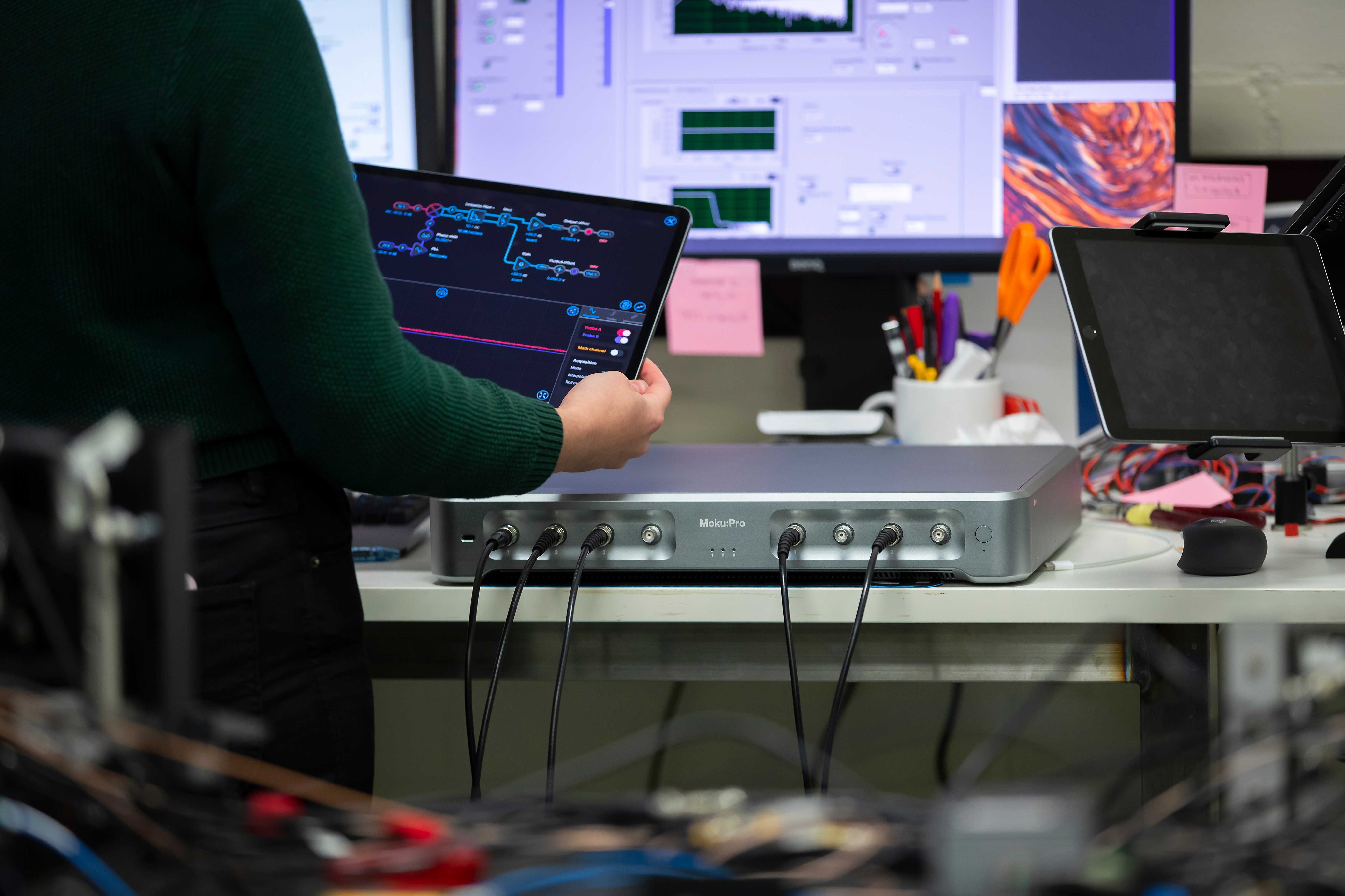 An engineer in a lab using Moku:Pro, holding an iPad